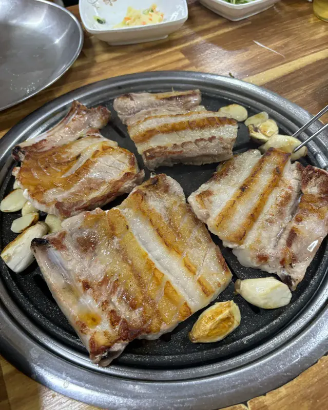 마장동숯불구이 시그니처 메뉴 — 고소하고 크리스피한 맛의 돼지 생갈비가 숯불에 구워지는 모습