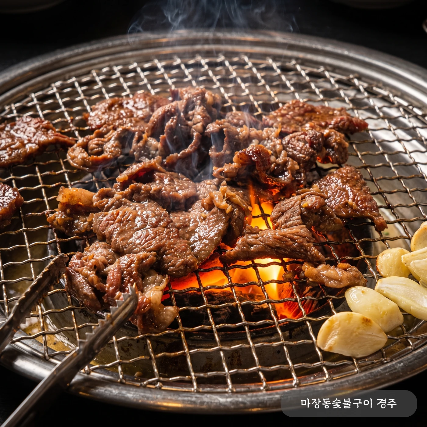 참숯 석쇠 위에서 직화로 구워지는 한우 양념구이 — 불꽃이 올라오는 숯불에 노릇하게 익는 양념한 한우와 구운 마늘