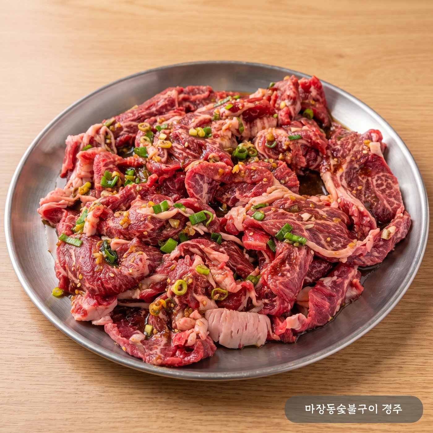 접시에 담긴 생 한우 양념구이 — 어머니 특제 양념에 재운 얇게 썬 한우 등심·정형육·업진살에 파와 통깨가 올라간 모습