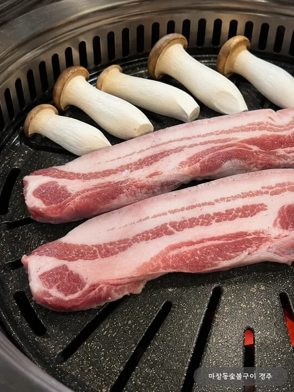 참숯 불판 위 돼지 오겹살 원육과 새송이버섯 — 굽기 시작 단계의 신선한 5겹 단면