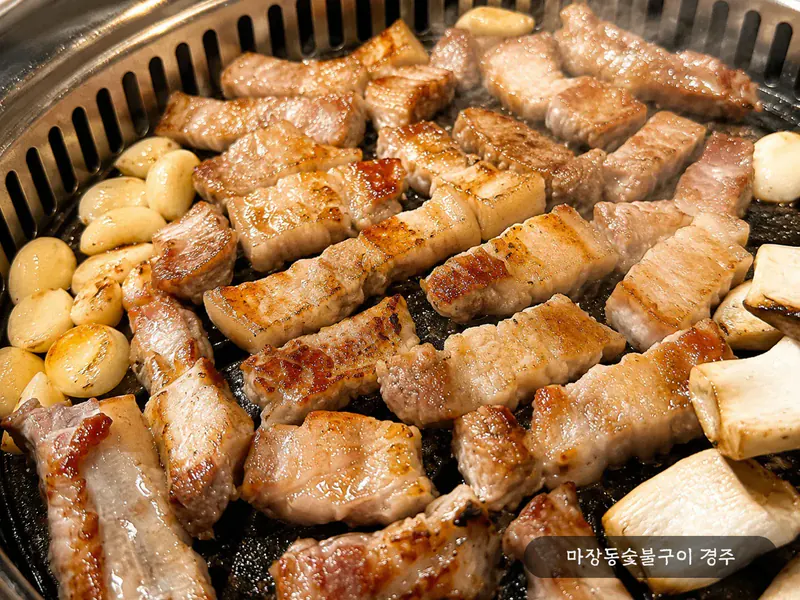 참숯 불판 위에서 노릇하게 구워지는 돼지 생갈비 — 통마늘·새송이버섯과 함께